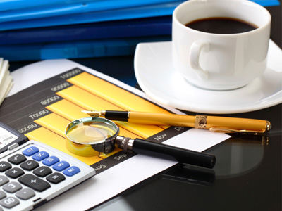 spy glass and calculator next to bar graph of financial information